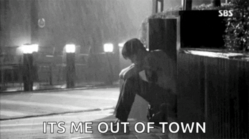 a black and white photo of a man sitting in the rain with the words `` it 's me out of town '' .