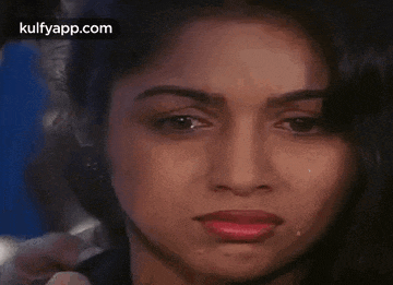 a close up of a woman 's face with a tear running down her cheek .