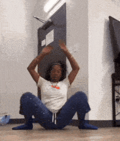 a woman is sitting on the floor with her legs crossed and her arms up