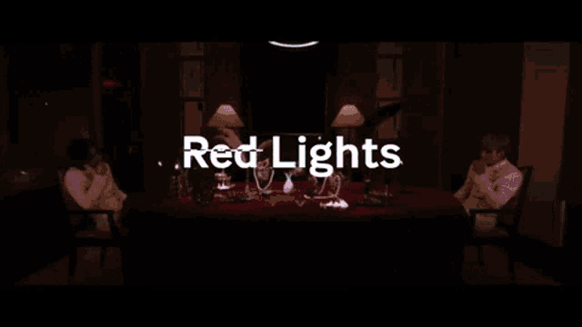 two people sit at a table in a dark room with the words red lights above them