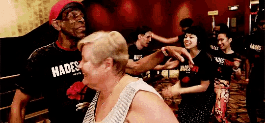 a man wearing a hades shirt is dancing with a woman