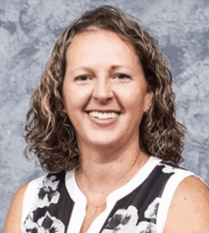 a woman with curly hair is smiling for the camera while wearing a black and white floral shirt .