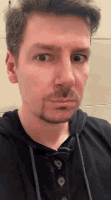 a man with a beard is wearing a black shirt and looking at the camera
