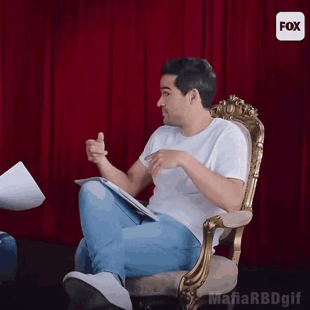 a man in a white shirt is sitting in a chair with a fox logo in the corner