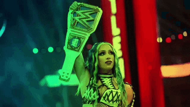 a female wrestler is holding a wrestling championship belt in the air .