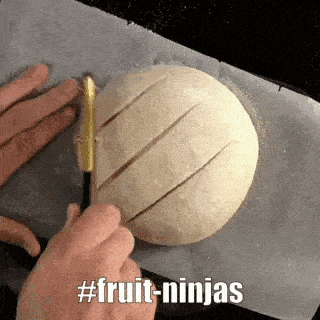 a person is cutting a loaf of bread with a knife on a baking sheet .