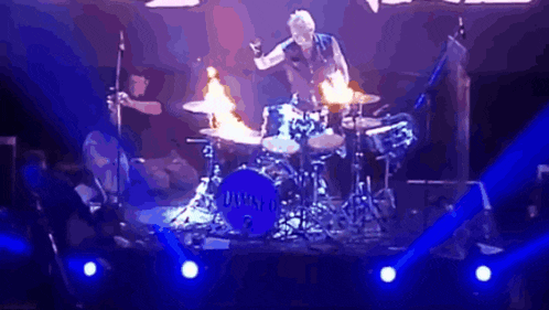 a man is playing drums on a stage with a drum set that says drums on it