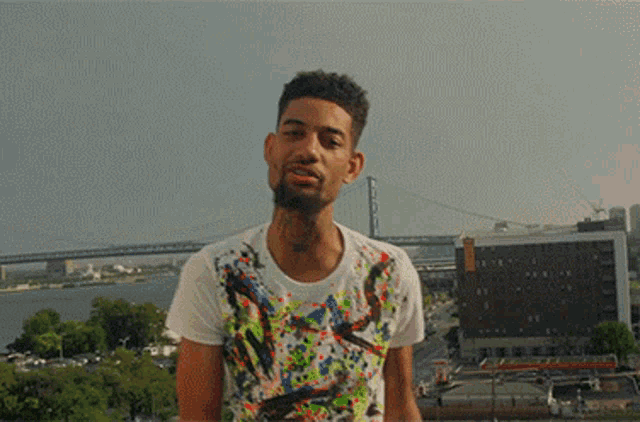 a man in a colorful shirt stands in front of a city