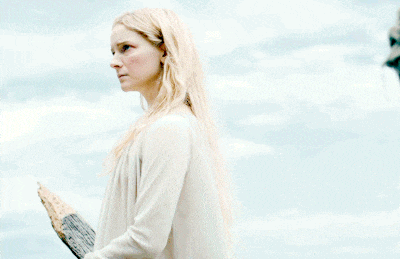 a woman in a white sweater holds a piece of wood