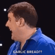 a man in a blue shirt is talking about garlic bread and laughing .