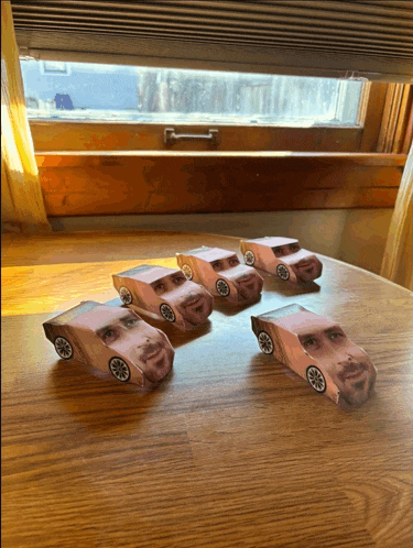 five paper cars with faces on them are sitting on a wooden table