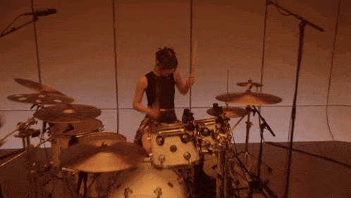a woman is playing drums in front of a window