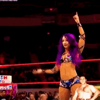 a woman with purple hair is in a wrestling ring with a man