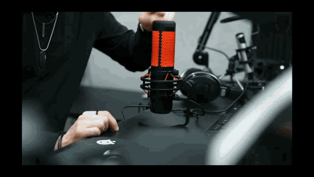 a person is holding a red and black microphone in front of a computer