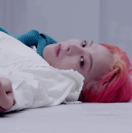 a woman with red hair is laying on the floor with a white shirt on .