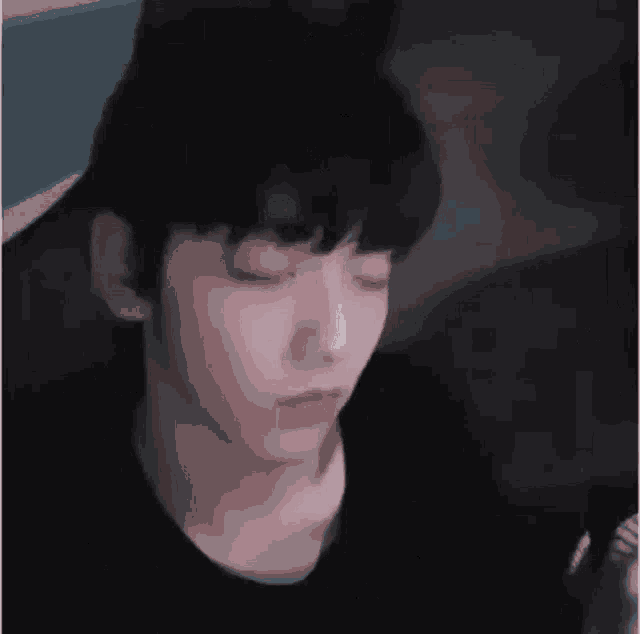 a close up of a person 's face with their eyes closed and a black shirt on .