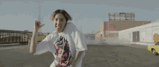 a man wearing a white shirt with a skull on it is standing in a parking lot