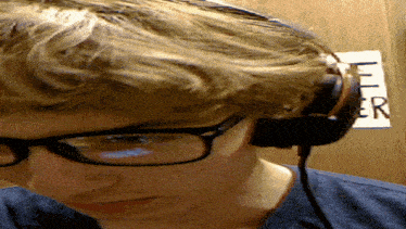 a young man wearing glasses and headphones is looking down