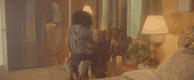 a woman is sitting on a chair with a child in a bedroom .