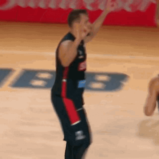 a basketball player is standing on a basketball court with his hands in the air .