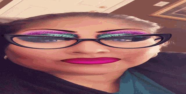 a woman wearing glasses has a pink lip sticking out of her mouth