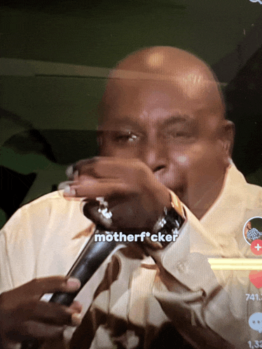 a man singing into a microphone with the words motherf * cker on the screen behind him