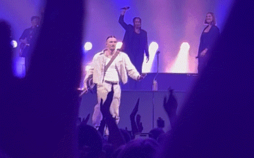 a group of people are standing on a stage with purple lights