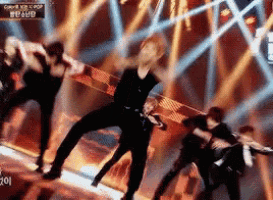 a group of people are dancing on a stage in front of a sign that says ' kpop ' on it .