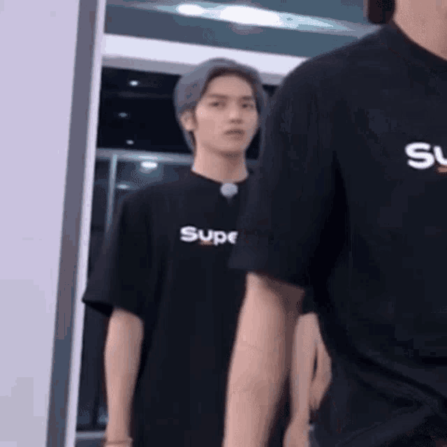 a man in a black supreme t-shirt is standing next to another man in a black shirt .