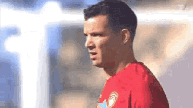 a man wearing a red shirt is standing on a soccer field .