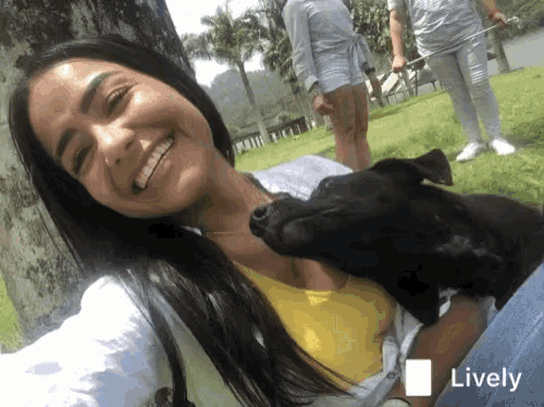 a woman holding a black dog with the word lively on the bottom right corner