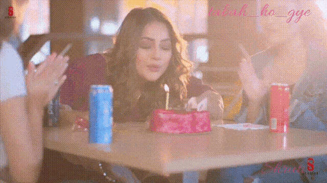 a woman is blowing out a candle on a birthday cake while sitting at a table .