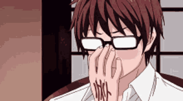 a man wearing glasses is covering his nose with his hand .