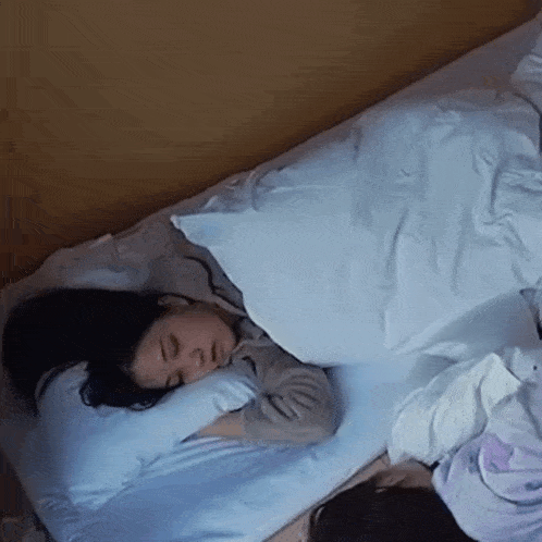 a woman is sleeping on a bed with a blue comforter