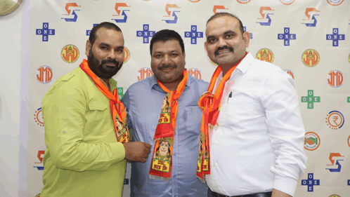 three men are posing for a picture and one of them has a scarf around his neck that says one world