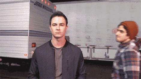 a man in a black jacket is standing next to another man in a plaid shirt .