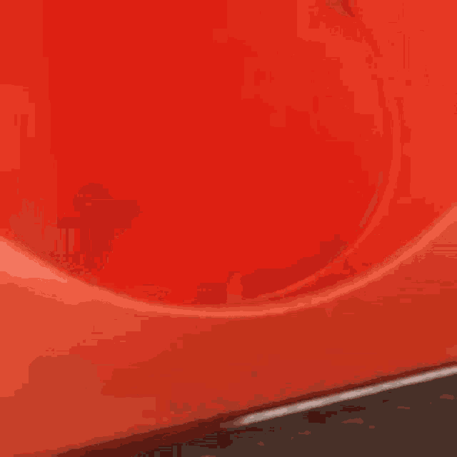 a little girl is sitting on a red slide covering her eyes