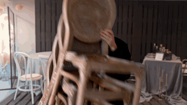 a person is holding a stack of chairs in a restaurant
