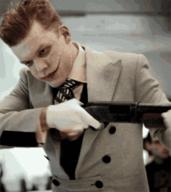 a man in a suit and tie is holding a gun in his hand