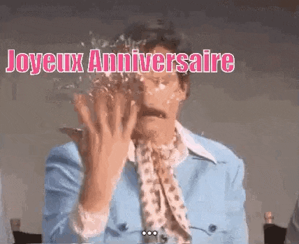 a man in a blue jacket and scarf is covered in icing and says joyeux anniversaire .