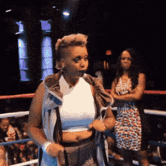 a woman is standing in a boxing ring with a towel around her shoulder