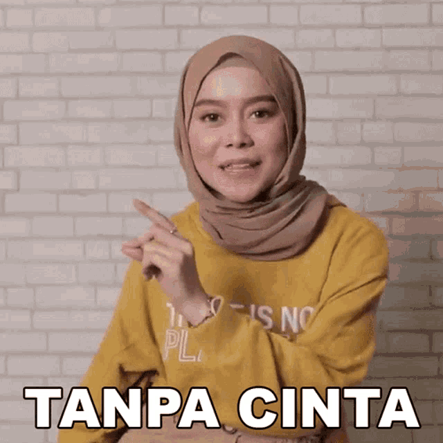 a woman wearing a hijab and a yellow shirt with the words tanpa cinta written on it