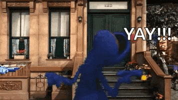 elmo from sesame street is dancing in front of a building and says yay