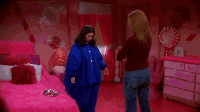 a woman in a blue coat is standing in a pink room