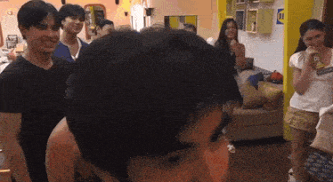 a group of people are standing around a man in a room .