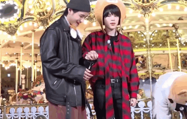 two men are standing in front of a merry go round