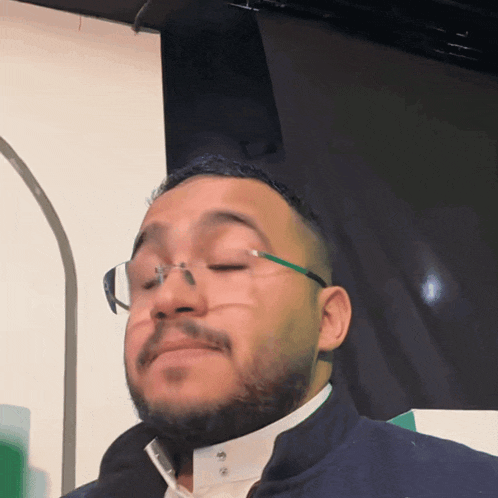 a man with a beard wearing glasses and a blue jacket