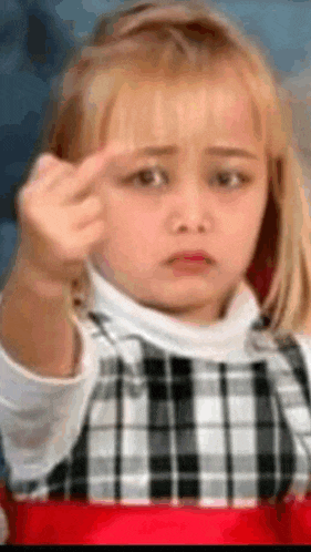 a little girl is making a funny face while giving the middle finger .