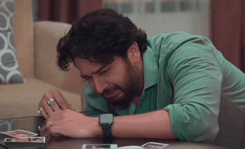 a man is laying on the floor crying while looking at a picture on a table .