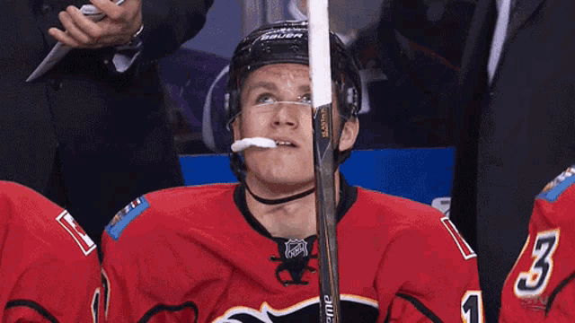 a hockey player with a stick in his mouth and the number 5 on his jersey